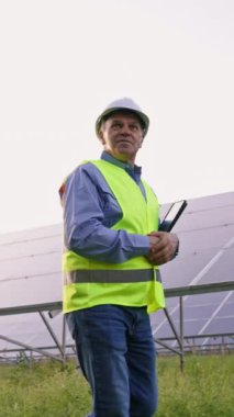 Güneş panelleri endüstriyel alanında çalışan olgun bir mühendis. Sert şapkalı profesyonel yetişkin adam yeni ekolojik güneş enerjisi inşaatında yürüyor. Elektrik, ekoloji, teknoloji kavramı