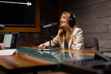 Dijital kayıt stüdyosunda çalışırken mikrofon kullanan kulaklıklı genç bir kadın. Mesleki meslek kavramı