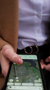 Sokakta dikey ekranlı cep telefonuyla haritayı yakınlaştıran genç iş kadınının dikey görüntüsü. İnternet teknolojisi kavramı