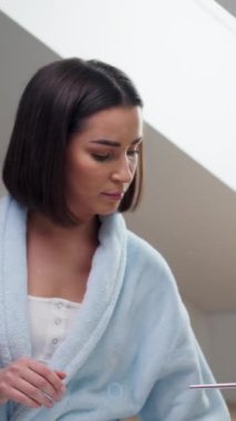 Bornozlu kadın aynanın önünde dururken dişlerini fırçalıyor. video 4K