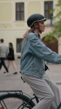 Sarışın, koruyucu kasklı, gülen bir kadın sokakta tek başına bisiklete biniyor. Bisiklet süren mutlu turistler. Seyahat, bisiklet kiralama, yaz konsepti.