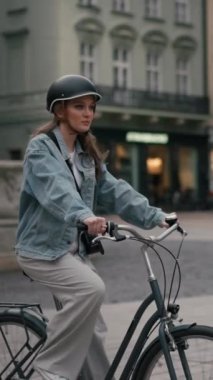 Şehir merkezinin yakınlarındaki sokakta bisiklet süren mutlu genç bir kadının yavaş çekim görüntüsü. Yaz yolculuğunda bisiklet kullanarak gülen kadın yaşam tarzı, ECO dostu.