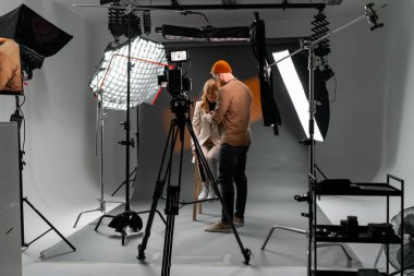 İyi donanımlı bir stüdyoda fotoğrafçı ve model, gelişmiş ışıklandırma ayarlarıyla mükemmel bir çekim yapıyorlar..