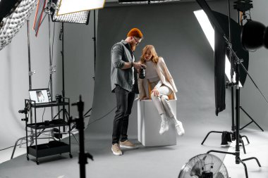 Moda çekimi için ışık ve ekipman ile profesyonel stüdyoda modelleri ayarlayan fotoğrafçı..