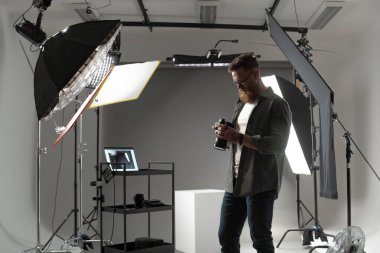 İyi donanımlı bir stüdyoda kamera ekipmanlarıyla çalışan profesyonel bir fotoğrafçı..