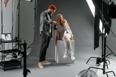 Fotoğrafçı bir stüdyo ortamında profesyonel bir fotoğraf çekimi sırasında ayarlama yaparken model pozu.