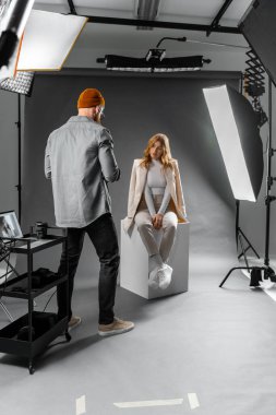 Fotoğrafçı profesyonel ışıklandırma ve ekipman ile bir stüdyo ortamında bir model yakalıyor.