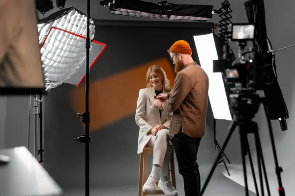 stock image Photographer adjusts lighting for professional studio photoshoot with female model in stylish outfit