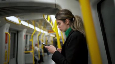 Akşamları tramvayda akıllı telefon ekranına bakan bir kadın. Yolculuk sırasında telefonla konuşan ciddi bir kadın.