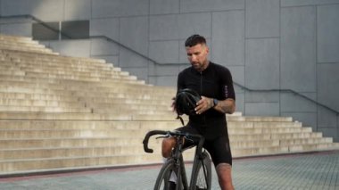 Canlı ve modern şehir ortamında bir bisikletçi kaskını şık motosikletinin yanına dikkatlice yerleştirir ve sürmeye hazırdır.