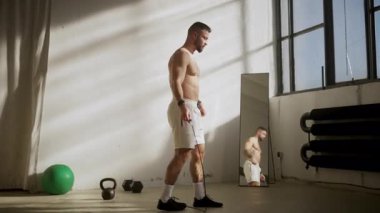 Formda bir adam, doğal ışıkla parlak bir spor salonunda atlama ipiyle enerjik bir şekilde egzersiz yapar.