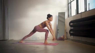 Kendini adamış bir yoga ustası parlak ve minimalist bir stüdyoda dinamik bir duruş sergiliyor.