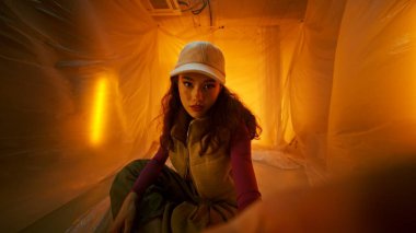 Şık ve modaya uygun bir model şık bir elbisenin içinde canlı ve renkli bir arkaplana karşı zarif bir poz verir.