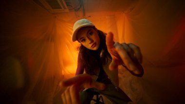 Yaratıcı jestler ve tarz sergileyen genç bir kadının göz alıcı ve büyüleyici bir görüntüsü.