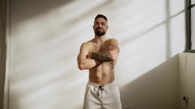 Atletik bir erkek model dinamik varlığını güvenli bir şekilde parlak ve aydınlık bir ortamda yayar.