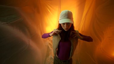 Şık bir model, yumuşak, parlak bir arka planı olan canlı bir düzende zarif bir şekilde poz verir.