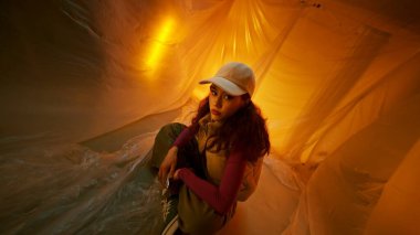 Şık bir genç kadın zarif bir şekilde tasarlanmış, canlı, sanatsal bir iç mekanda poz veriyor.