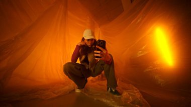 Şık bir birey, canlı, sıcak ve soyut bir sanat ortamında rahatça poz veriyor.