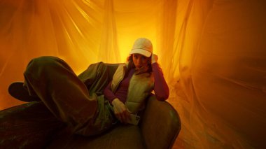 Genç bir birey sıcak ve sanatsal bir ortamda rahatça yaslanır.