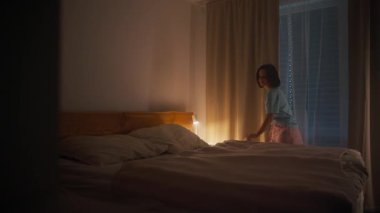 Bir kız sıcak, rahat bir yatak odası sahnesinde yatağını hazırlar. Huzurlu bir gece için mükemmeldir.