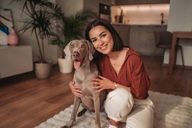 Bir kadın, evcil köpeğiyle lüks ve rahat bir yerde mutlu bir anın tadını çıkarır.