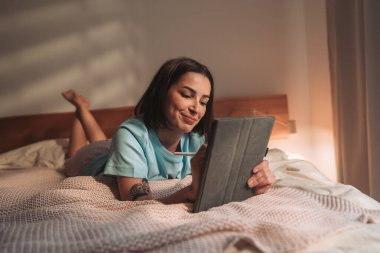 Neşeli bir kadın, rahat bir yatakta dinlenirken hapını mutlu bir şekilde kullanıyor.