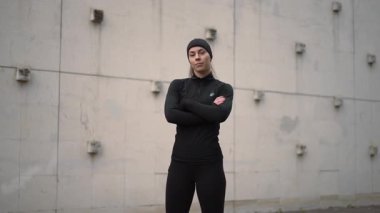 Kendine güvenen bir atlet yoğun bir şehir ortamında duruyor, güç ve ilham verici bir kararlılık sergiliyor