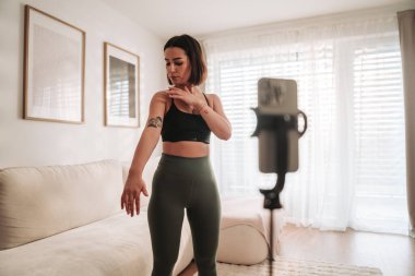 Genç bir kadın zarif bir şekilde çeşitli yoga pozlarını güzel dekore edilmiş oturma odasında sergiliyor.