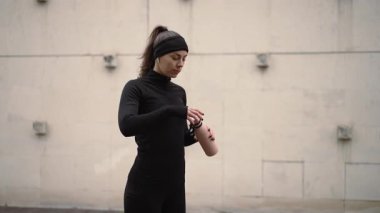 Formda bir kadın, açık havada canlı bir ortamda egzersiz yaptıktan sonra şişeden ferahlatıcı su içer.