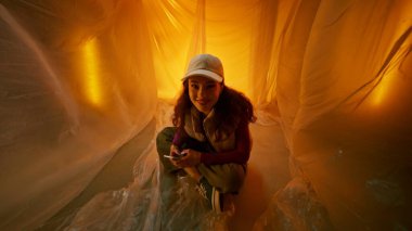 Genç bir kız sıcak turuncu ışıkla dolu canlı, plastiksi bir dünyayı keşfediyor.