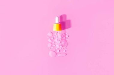 Yellow pipette transparent drops of serum moisturized bottle on pink background. Essence hyaluronic acid close up. Spa, beauty, skincare product.