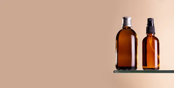 Glass brown bottle with cosmetic oil and spray serum, essential or serum stand on beige pastel background. Herbal homeopathic products. Natural organic spa cosmetics