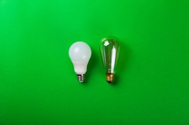 Yeşil arka planda parlak bir lamba ve yol gösteren bir lamba. Enerji verimliliği kavramı. Düz yatıyordu. Ekolojiyi kavra, dünyayı kurtar, fikri, enerjiyi, ekonomiyi, tasarrufu. Dünya günü