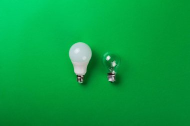Yeşil arka planda parlak lambalar ve lambalar var. Enerji verimliliği kavramı. Düz yatıyordu. Ekolojiyi kavra, dünyayı kurtar, fikri, enerjiyi, ekonomiyi, tasarrufu. Dünya günü