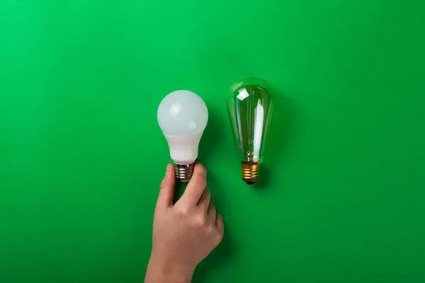 Idea male hand touch LED light bulbs on green color background. Flat lay with copy space. Concept ecology, save planet earth, idea, save energy, economy, saving. Earth day