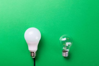 Yeşil arka planda parlak bir lamba ve yol gösteren bir lamba. Enerji verimliliği kavramı. Düz yatıyordu. Ekolojiyi kavra, dünyayı kurtar, fikri, enerjiyi, ekonomiyi, tasarrufu. Dünya günü