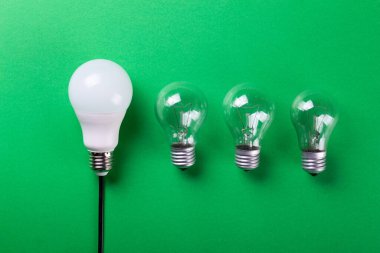 Yeşil arka planda parlak bir lamba ve yol gösteren bir lamba. Enerji verimliliği kavramı. Düz yatıyordu. Ekolojiyi kavra, dünyayı kurtar, fikri, enerjiyi, ekonomiyi, tasarrufu. Dünya günü