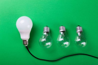 Yeşil arka planda parlak bir lamba ve yol gösteren bir lamba. Enerji verimliliği kavramı. Düz yatıyordu. Ekolojiyi kavra, dünyayı kurtar, fikri, enerjiyi, ekonomiyi, tasarrufu. Dünya günü