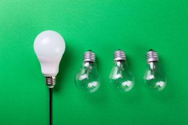 Yeşil arka planda parlak bir lamba ve yol gösteren bir lamba. Enerji verimliliği kavramı. Düz yatıyordu. Ekolojiyi kavra, dünyayı kurtar, fikri, enerjiyi, ekonomiyi, tasarrufu. Dünya günü