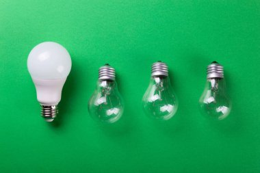 Yeşil arka planda parlak bir lamba ve yol gösteren bir lamba. Enerji verimliliği kavramı. Düz yatıyordu. Ekolojiyi kavra, dünyayı kurtar, fikri, enerjiyi, ekonomiyi, tasarrufu. Dünya günü