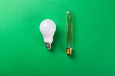 LED lambalar ve parlak Eddison lambası yeşil arka planda izole edilmiş. Seçici odaklanma, gürültü. Enerji tasarrufu lambası