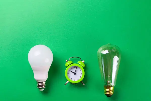 Flatlay Clock with light bulb, calculator on a green background. Minimalism. Top view. Concept ecology, save planet earth, idea, save energy, economy, saving. Earth day