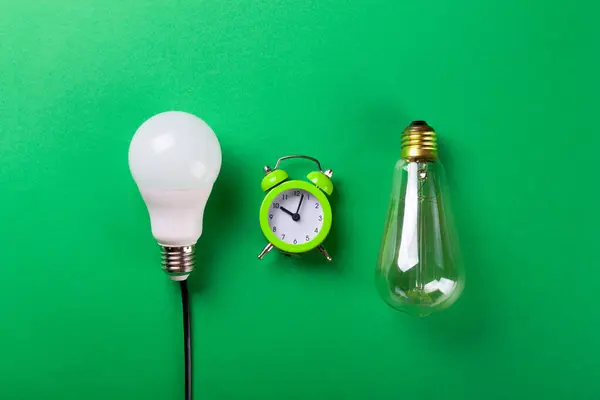 Flatlay Clock with light bulb, calculator on a green background. Minimalism. Top view. Concept ecology, save planet earth, idea, save energy, economy, saving. Earth day