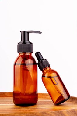 Kara kehribar cam şişe serumu, ahşap plaka. Doğal cilt bakımı SPA güzellik ürünü tasarımı. Beyaz arka planda mineral organik yağ kozmetiği. Model-up. Yağlı pipet. Yüz ve vücut tedavisi. Düz yatıyordu