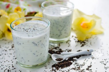 Beyaz arka planda cam bir fincanda chia tohumları olan yoğurt.