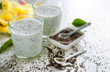 Beyaz arka planda cam bir fincanda chia tohumları olan yoğurt.