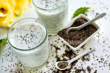 Beyaz arka planda cam bir fincanda chia tohumları olan yoğurt.