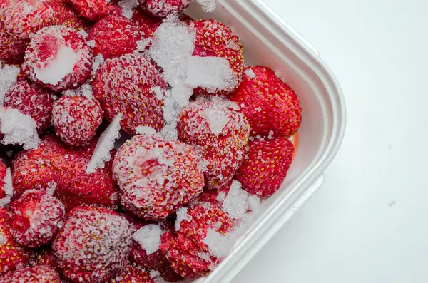 stock image Frozen homemade strawberries in a plastic container on a white background