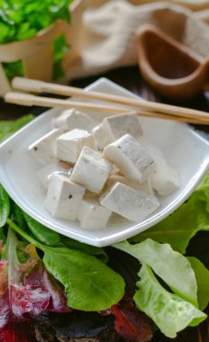 Taze vejetaryen ürünü, tofu. Baharat ve salata yapraklarıyla marine edilmiş bir tabakta soya grisi tofu.