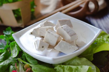 Taze vejetaryen ürünü, tofu. Baharat ve salata yapraklarıyla marine edilmiş bir tabakta soya grisi tofu.